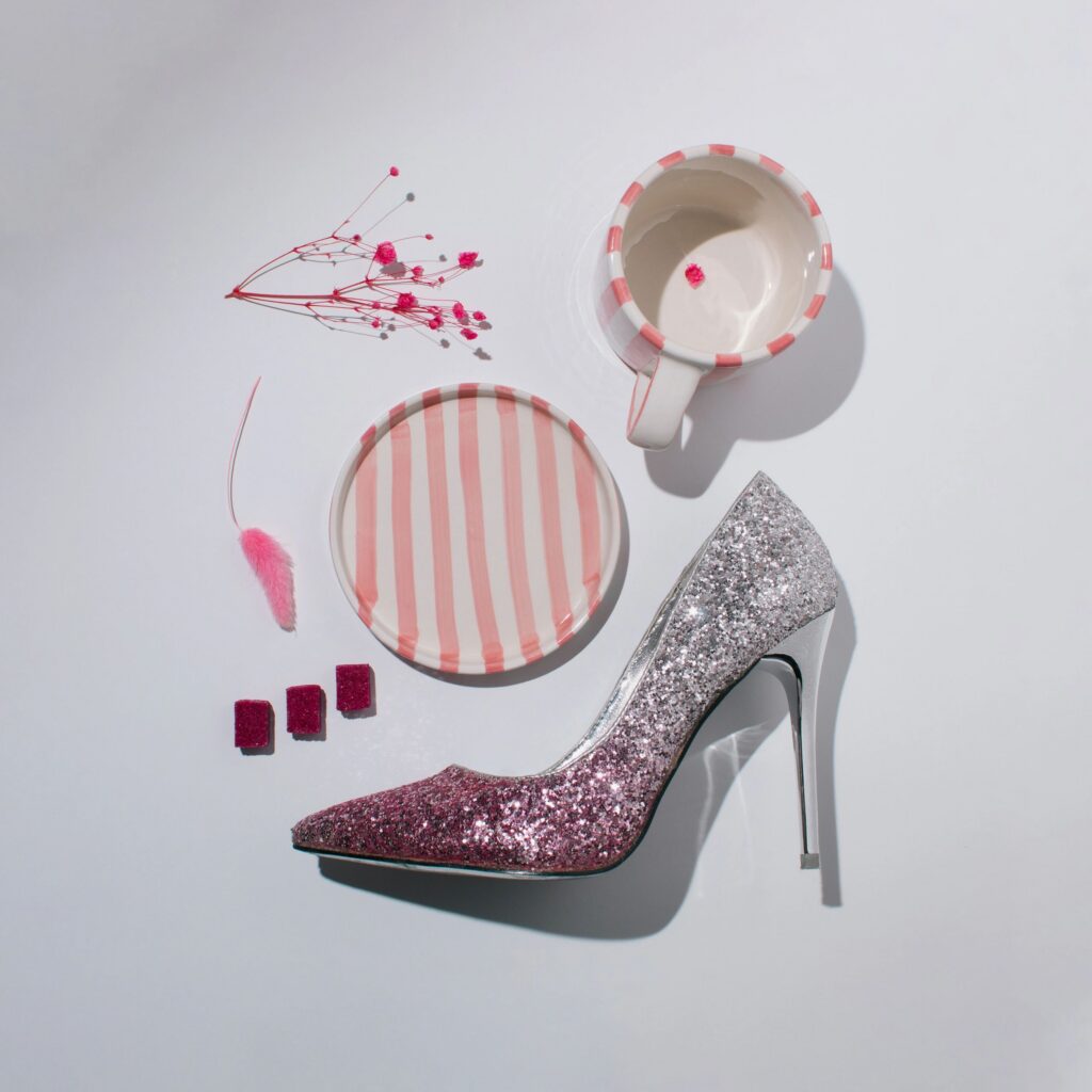 Pink glitter high heel shoe with coffee cup and flowers on white background